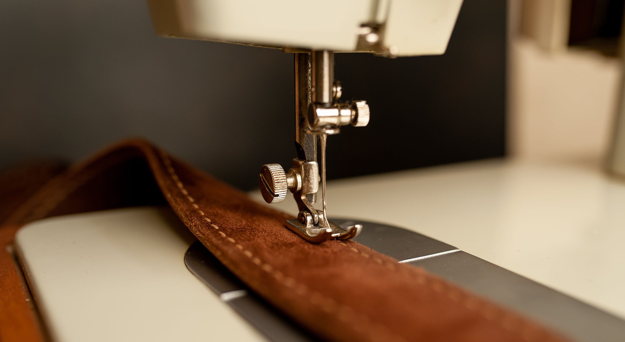 Background type of sewing machine, leather belt sewing process. Leather workshop.